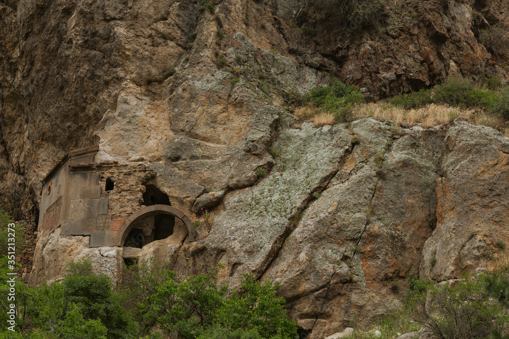 Old historic monastery with arched entrance constructed in rock in mountainous area