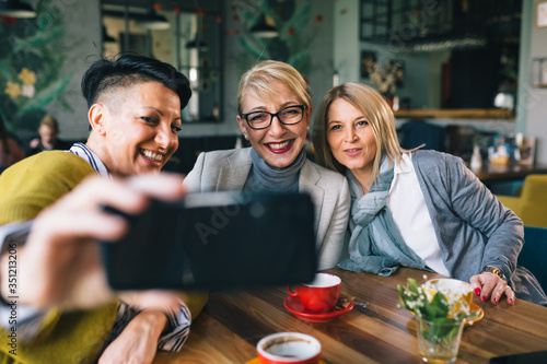 women friends having coffee break at cafe  taking pictures with smartphone