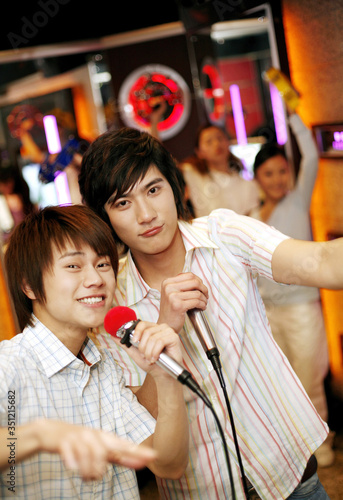 Two men singing together in karaoke bar