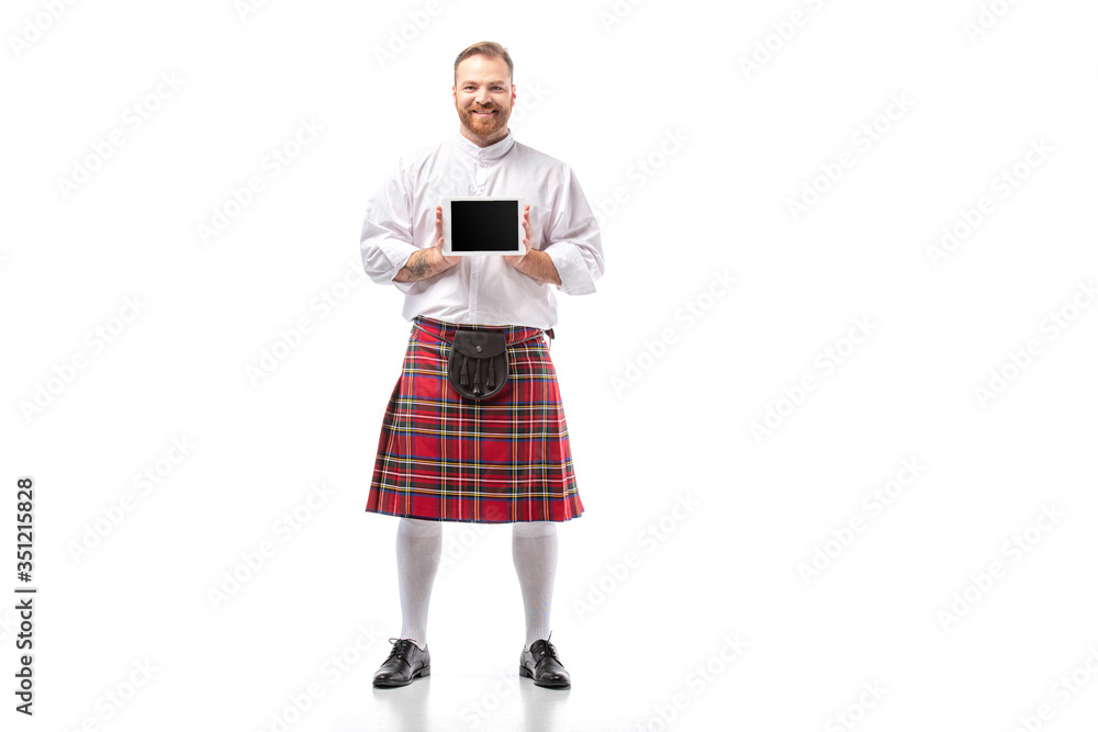 smiling Scottish redhead man in red kilt presenting digital tablet on white background smiling Scottish redhead man in red kilt presenting digital tablet on white background