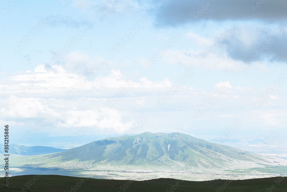 Picturesque mountain litting by sunlight. Amazing summer landscape of highland valley and blue sky with clouds