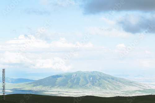 Picturesque mountain litting by sunlight. Amazing summer landscape of highland valley and blue sky with clouds