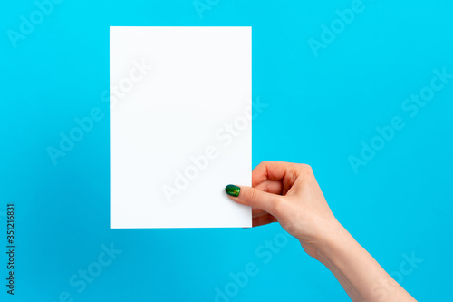 Woman hand holding blank card on blue background