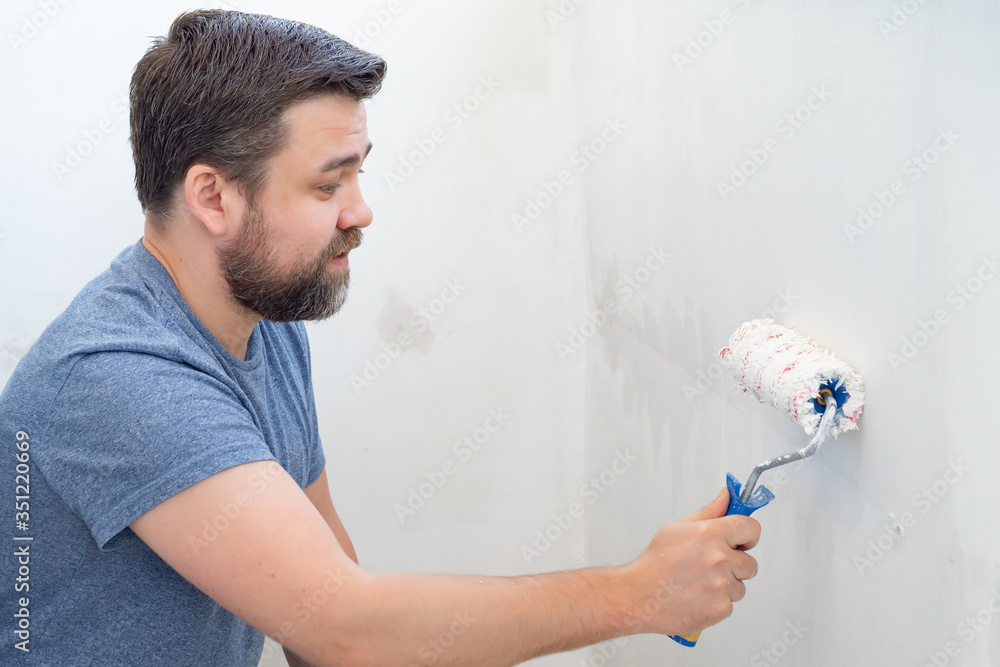 man painting wall roller with white paint. man painting wall roller with white paint.