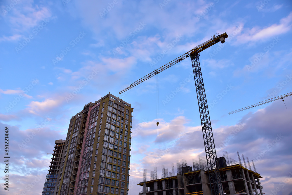 Fototapeta premium Tower crane in action on sunset sky background