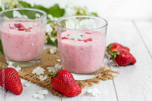 Strawberry and yogurt smoothies on a white background. Decorated with elderberry flowers and strawberries. Healthy nutrition, diet.
