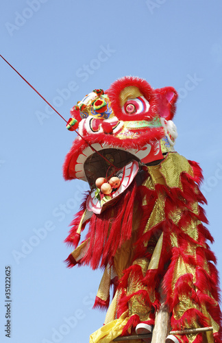 Performer in lion costume eating the hanging fruits and vegetable