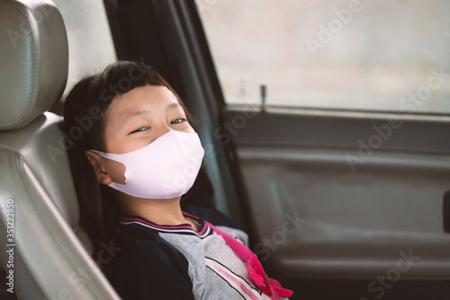 Asian little girl in a face mask from a car window. Hygiene mask protection coronavirus or covid-19