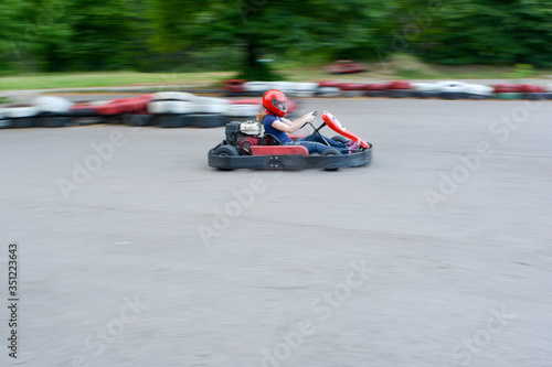 Kart racing or karting. Racing car on the road. The girl in the go-kart at speed. Blurred background.