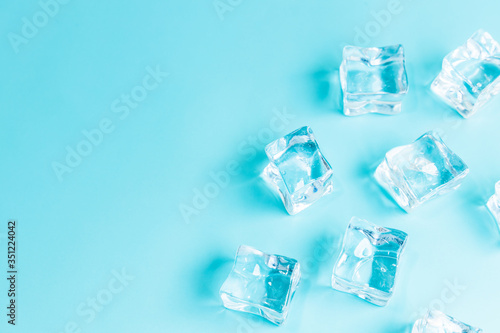 Ice cubes on blue background  Cubes of ice on a light blue background  Flat lay  top view  with copy space and field for text.