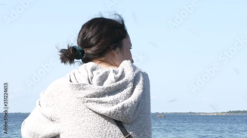 Handheld shot of a woman alone by the sea, looking out over barren skerries and De Geer moraines, Gulf of Botnia, Finland photo