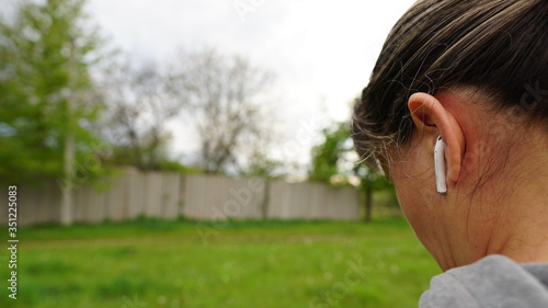Wireless earphone in woman's ear. A man is talking through a wireless earphone. Side view