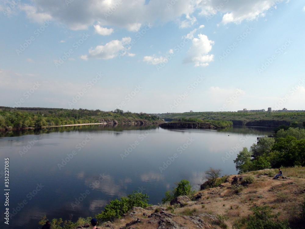 Panorama of the old channel of the Dnieper that reflects on its mirror surface a cloudy blue sky.