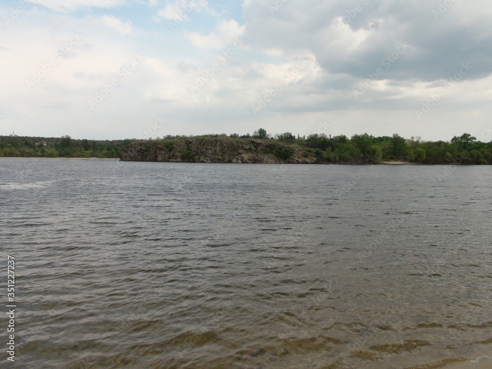 Amazing color change of the water surface of the restless Dnieper in stormy weather on the background of the island of Baida on the horizon.