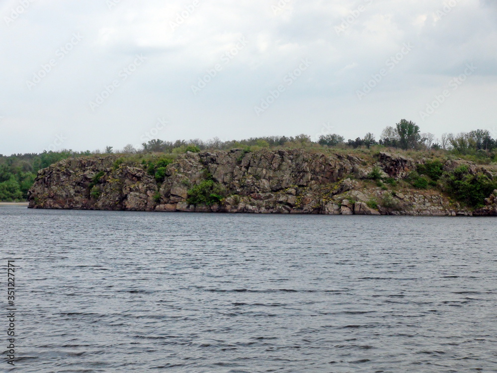 Amazing color change of the water surface of the restless Dnieper in stormy weather on the background of the island of Baida on the horizon. Amazing color change of the water surface of the restless Dnieper in stormy weather on the background of the island of Baida on the horizon.