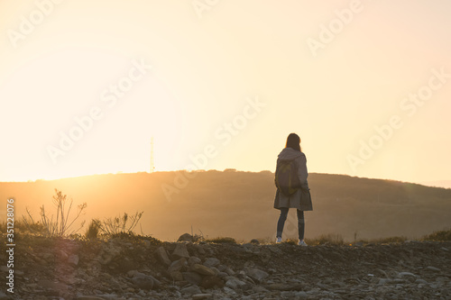 Young girl walking along a stone slope in the sunset rays on a background of hills. Tourism and outdoor concept.