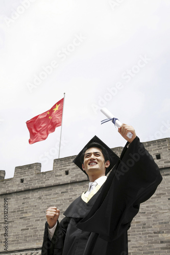 Man in graduation robe holding scroll photo