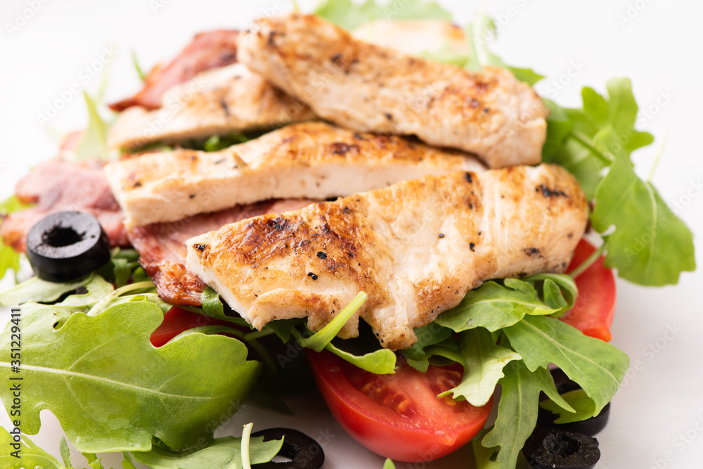 A chicken salad with rucola bacon and tomato