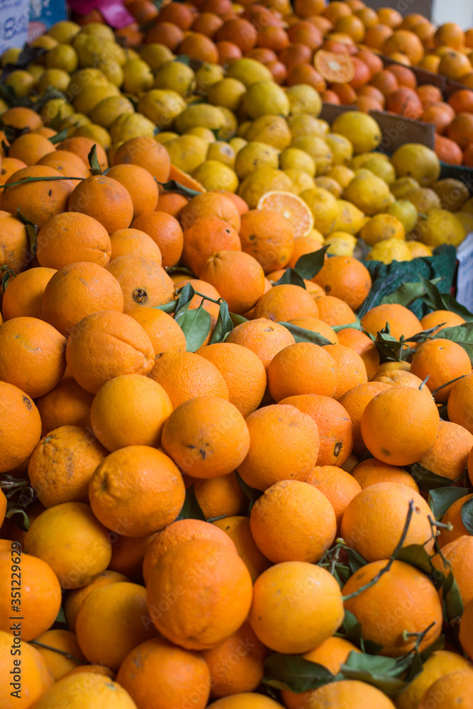 Fresh organic juicy orange fruits, lemons, mandarins lying on counter on street food market, farmers fair, greengrocer's shop. Colorful food, healthy vegan vegetarian lifestyle concept.