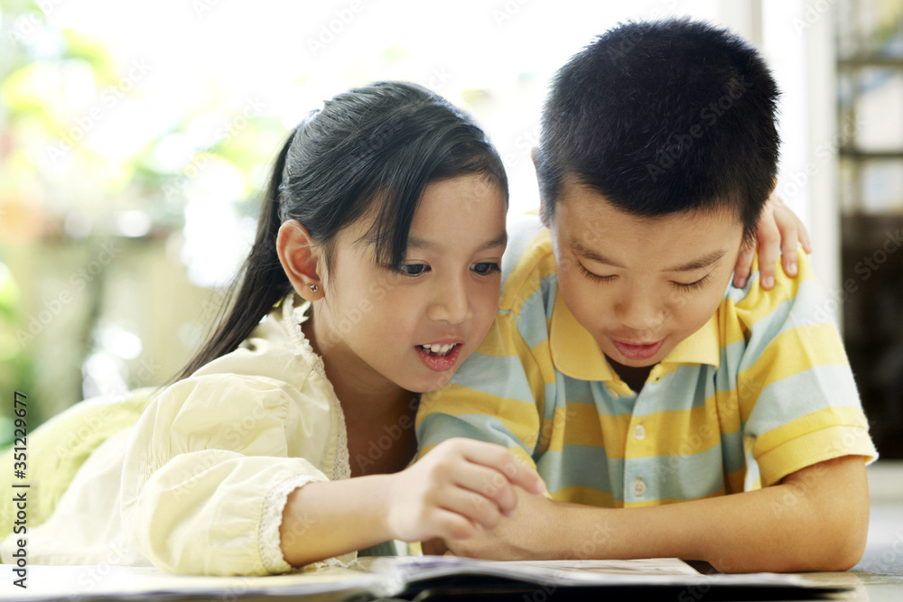 Brother and sister reading magazine together Brother and sister reading magazine together