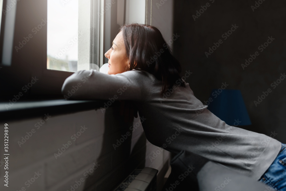 Woman sitting alone at home looking out window Woman sitting alone at home looking out window