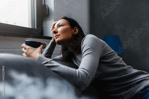 Woman sitting alone at home looking out window