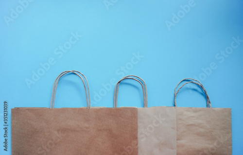 Top view of empty line of craft paper bags on blue background. Flat lay on contrast background, zero waste. Garbage recycling. Template or Mockup for designers. stop plastic pollution