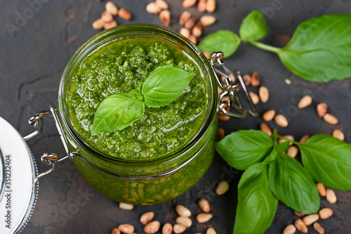 Homemade pesto sauce fresh Basil and nuts on dark background.