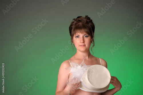 brunette on a green background in the studio closing the hat photo