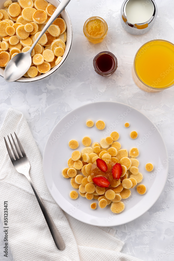 Tiny mini pancake cereal. Home made breakfast with raspberries, jam and juice on gray background Tiny mini pancake cereal. Home made breakfast with raspberries, jam and juice on gray background