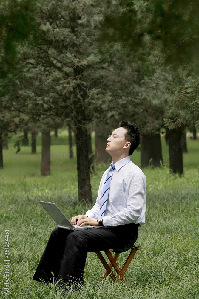Businessman closing his eyes while using laptop Businessman closing his eyes while using laptop