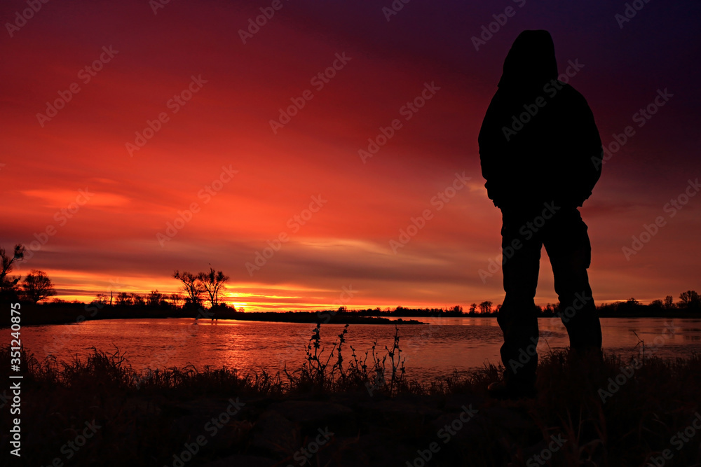 The man watches Colorful sunrise by the Odra River, Germany.