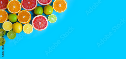 Blue background with different sliced citrus - oranges  grapefruits  lemons and limes. Flat layout with space for text. Banner