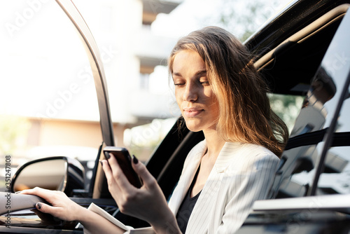 Business woman is using car transportation while working on phone