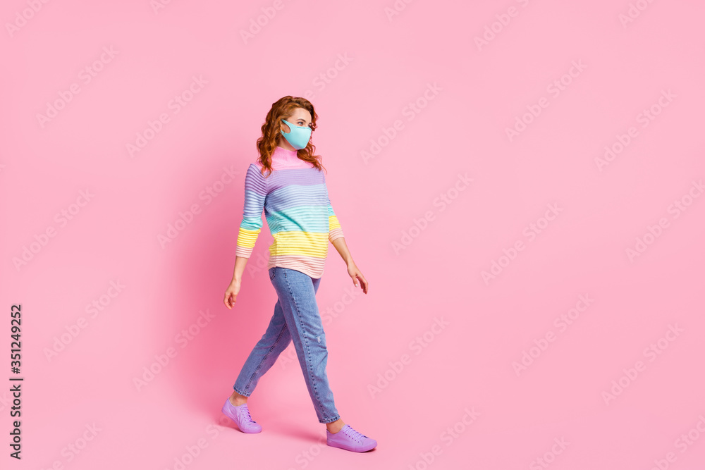 Full length profile photo of pretty foxy lady keep social distance walk outside go supermarket good mood wear protect face mask jeans pullover shoes isolated pink color background Full length profile photo of pretty foxy lady keep social distance walk outside go supermarket good mood wear protect face mask jeans pullover shoes isolated pink color background