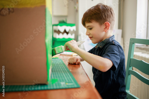 Boy painting a cardboard dinosaur costume