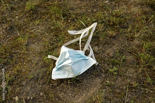 Surgical face mask in dirt. Littering medical mask in park. photo