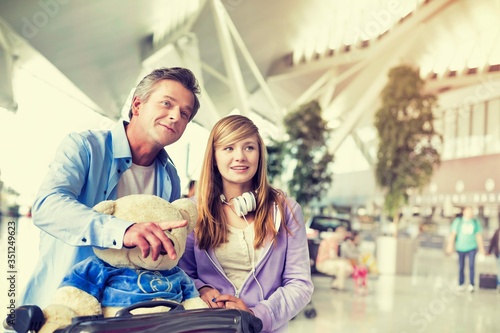Foto Portrait of mature man pushing baggage cart while walking with her daughter in a