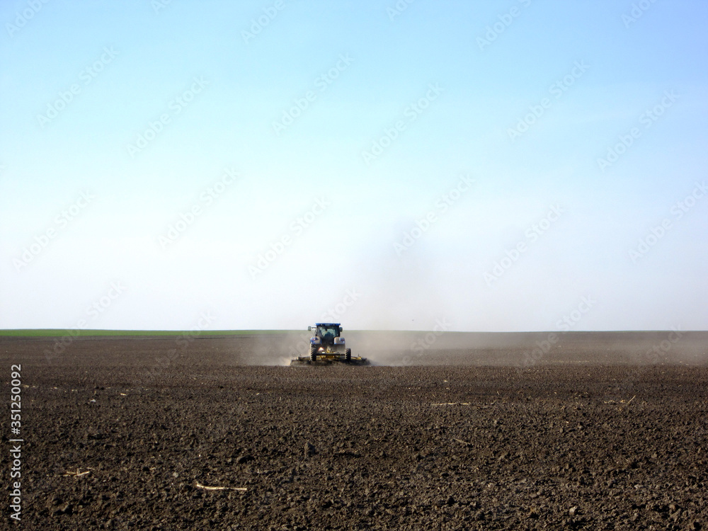 Obraz premium Plowed field by tractor in brown soil on open countryside nature