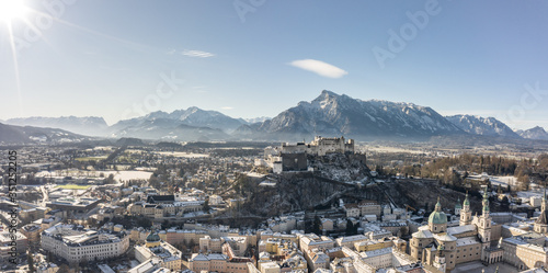 Panoramic aerial drone view of snowy Hohensalzburg fortress with view of Unesberg mountain in winter morning