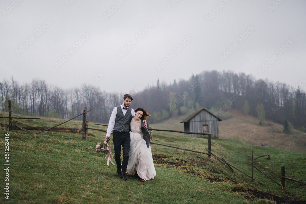 Romantic, young and happy caucasian couple in wedding clothes hugging on the background of beautiful mountains. Love, relationships, romance, happiness concept. Bride and groom traveling  together.