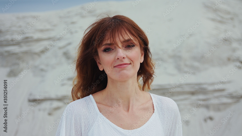SLOW MOTION: Beautiful sensual Red hair woman fashion portrait with long white and red dress walking on the white sand beach SLOW MOTION: Beautiful sensual Red hair woman fashion portrait with long white and red dress walking on the white sand beach