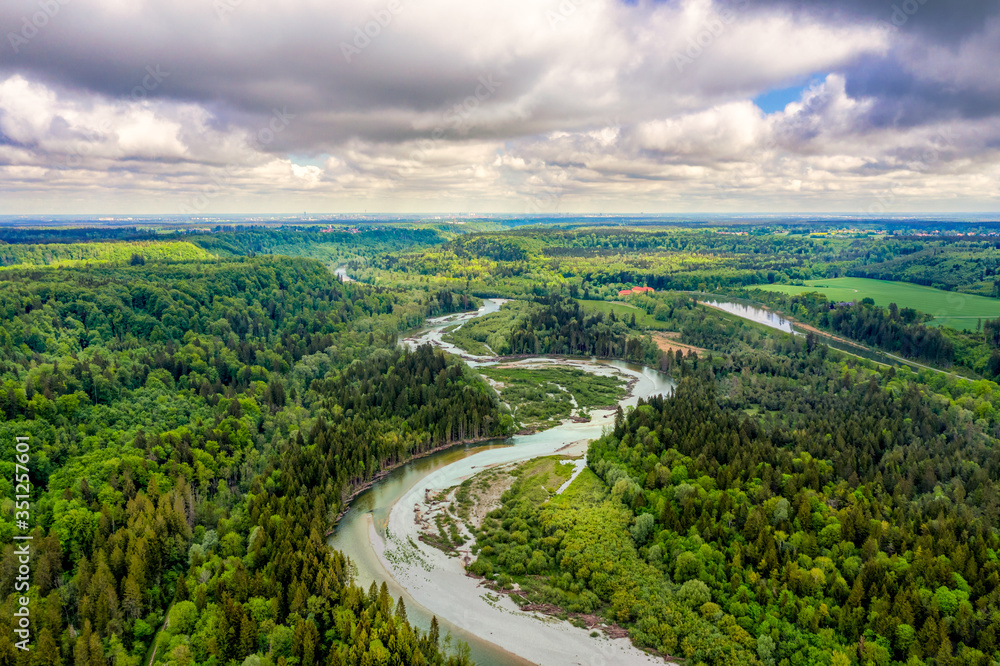 Aerial view at the curvy Isar river at a sunny but cloudy day from nearly 100m from above in southern bavaria, germany. Beautiful nature at springtime.