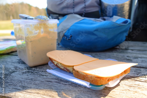 Snack sandwiches in the open air after a walk in nature. In the background is a backpack.