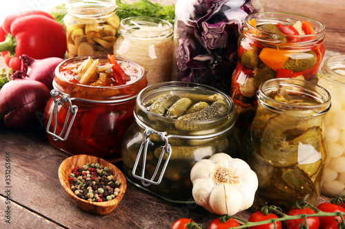 Preserves vegetables in glass jars. Pickled Cucumber, carrot, fermented cabbage and onions on rustic background