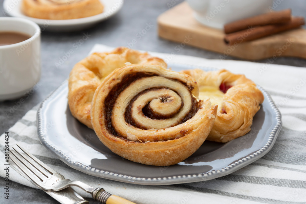 Danish pastry with coffee cup for breakfast. Cinnamon buns, fresh pastry for breakfast. Copy space. Danish pastry with coffee cup for breakfast. Cinnamon buns, fresh pastry for breakfast. Copy space.