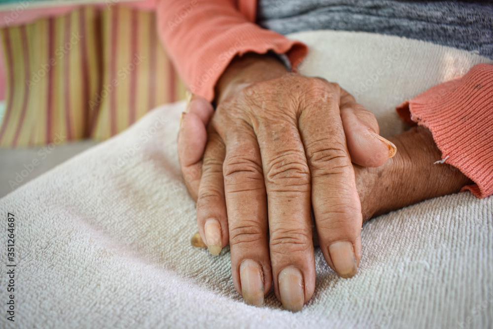 Fototapeta premium The hand of the sick old woman rests on the lap. Mental health care at home.