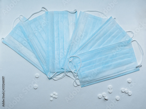 blue medical masks on a white background and pills