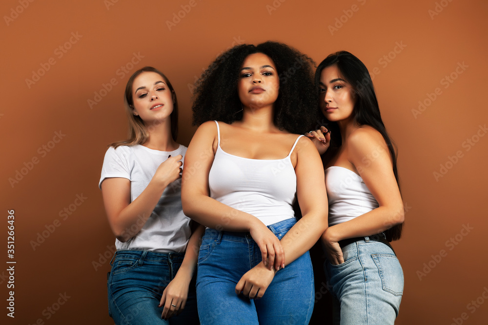 young pretty asian, caucasian, afro woman posing cheerful together on brown background, lifestyle diverse nationality people concept young pretty asian, caucasian, afro woman posing cheerful together on brown background, lifestyle diverse nationality people concept