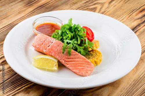 salmon with salad and vegetables - dish on a wooden background